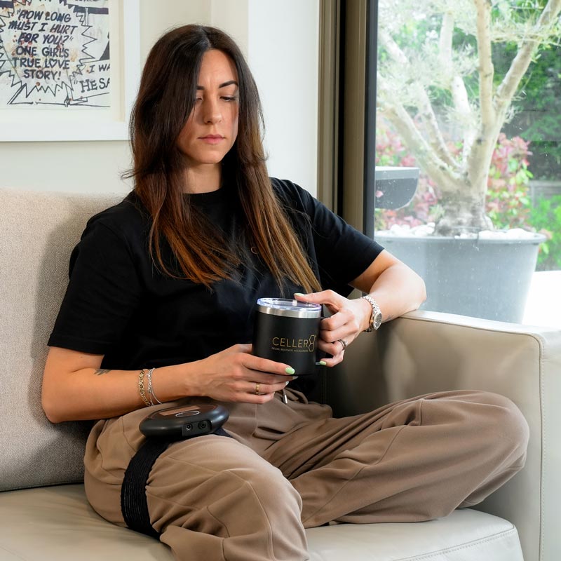 Women holding mug while sat on sofa