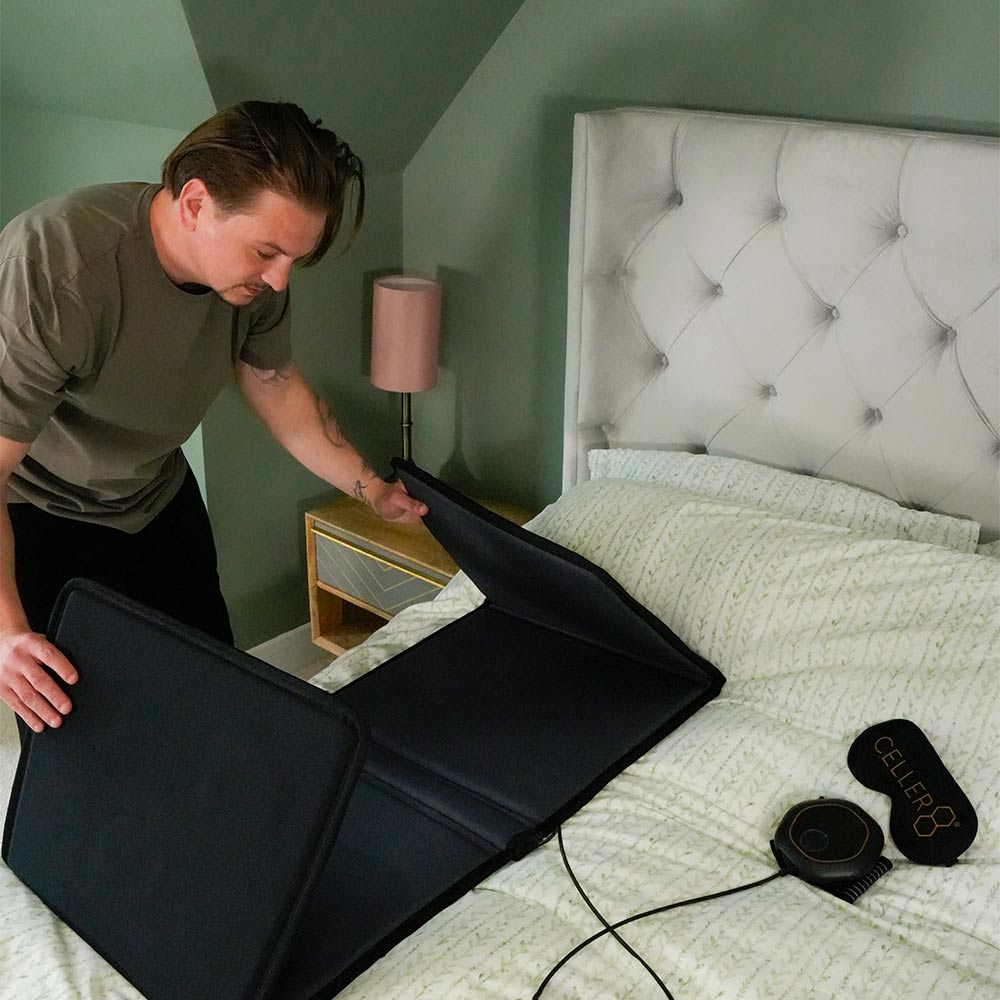 Man unfolding full body mat onto bed